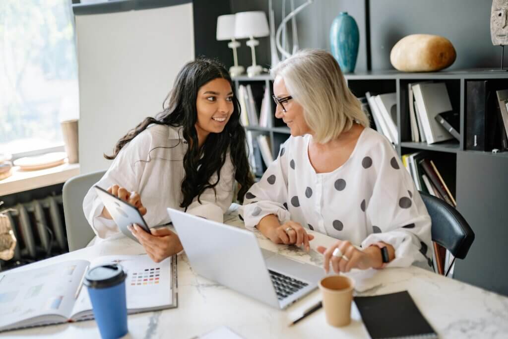 Two businesswomen engaged in a productive meeting around a laptop and tablet in a contemporary office.