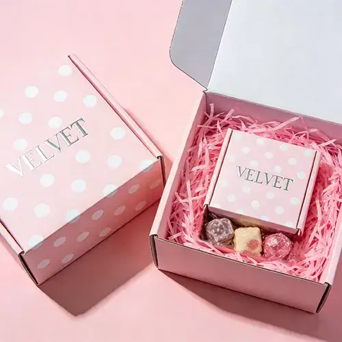 Pastel pink mailer box with shredded paper filler for gourmet gifts